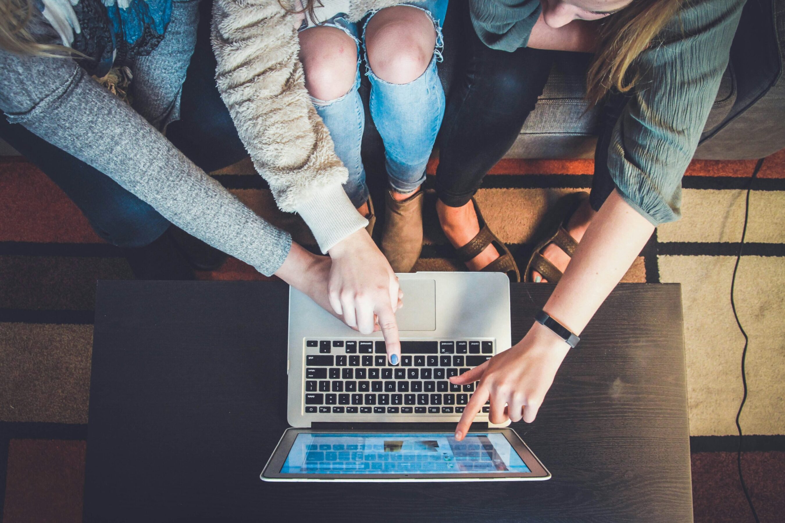 group of people collaborating and pointing to laptop scren