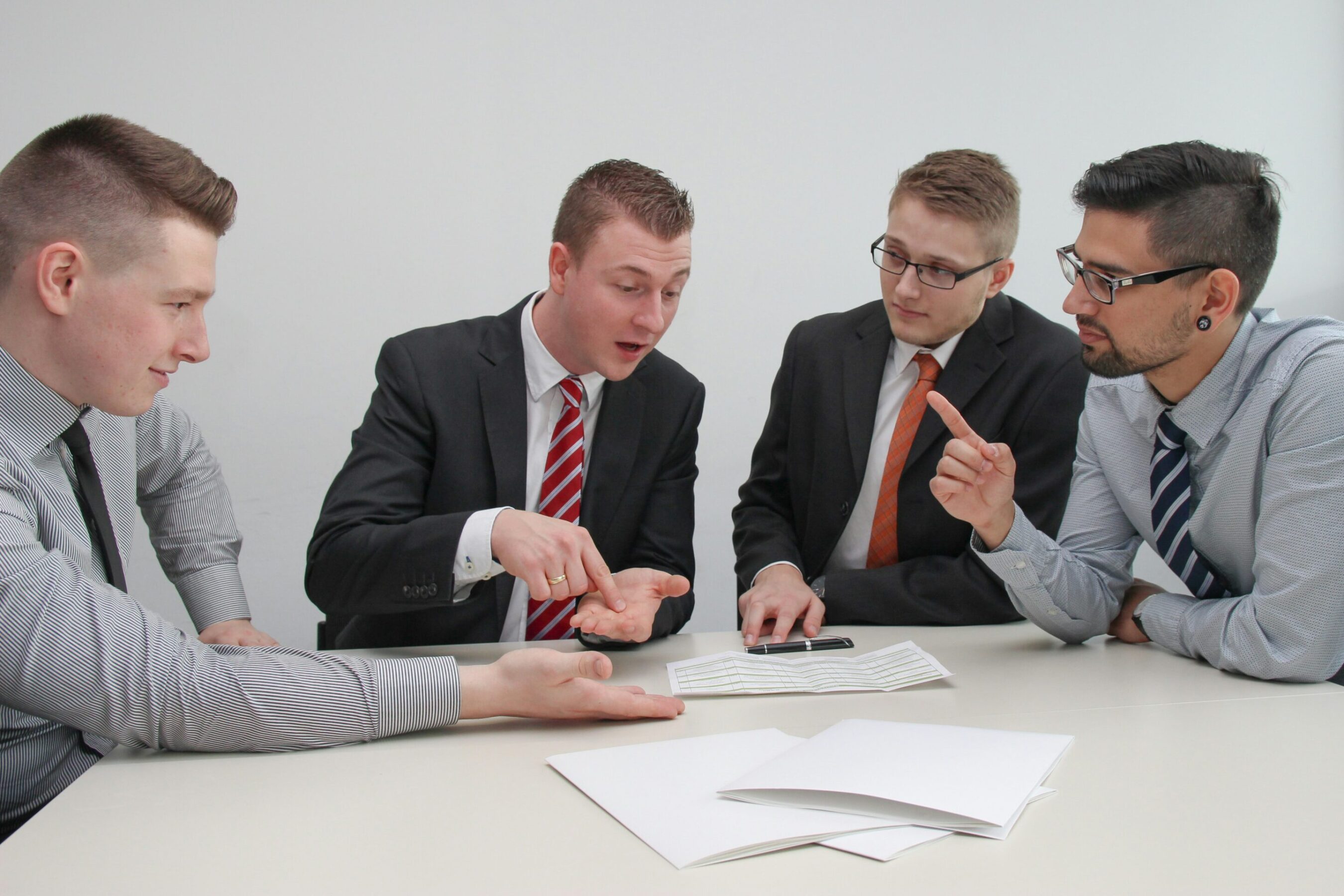 sebastian-herrmann-6jAq8MkbULo-unsplash Four men sitting at desk in discussion